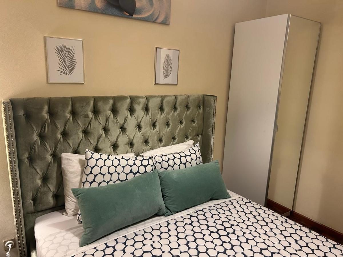 Quarto do Minho AL com cabeceira verde e almofadas decorativas